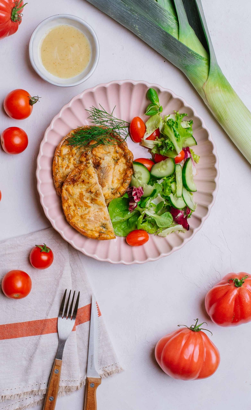 Mini tarta z wędzonym pstrągiem, karmelizowanymi porami i koperkiem, mix sałat z pomidorkami i ogórkiem