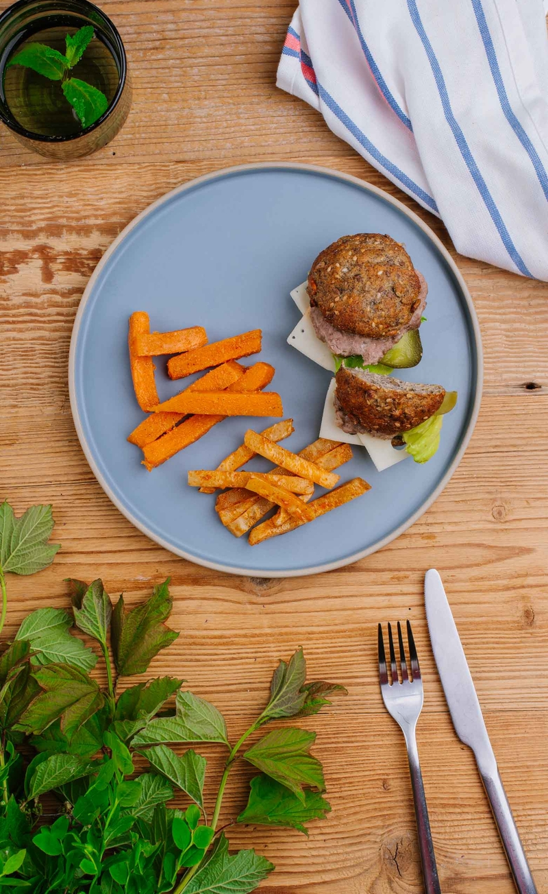 Burger wołowy z serem cheddar w bułce proteinowej z sezamem, pieczone słupki batata i selera